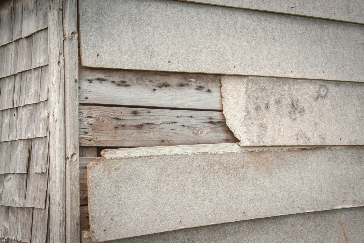 Worn wooden wall with peeling paint needing new siding